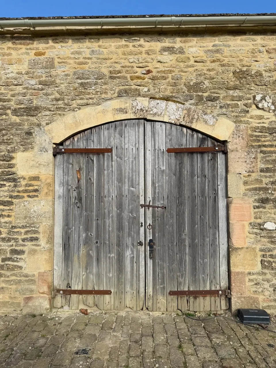The same arched barn doors before work began, weathered grey and stuck shut