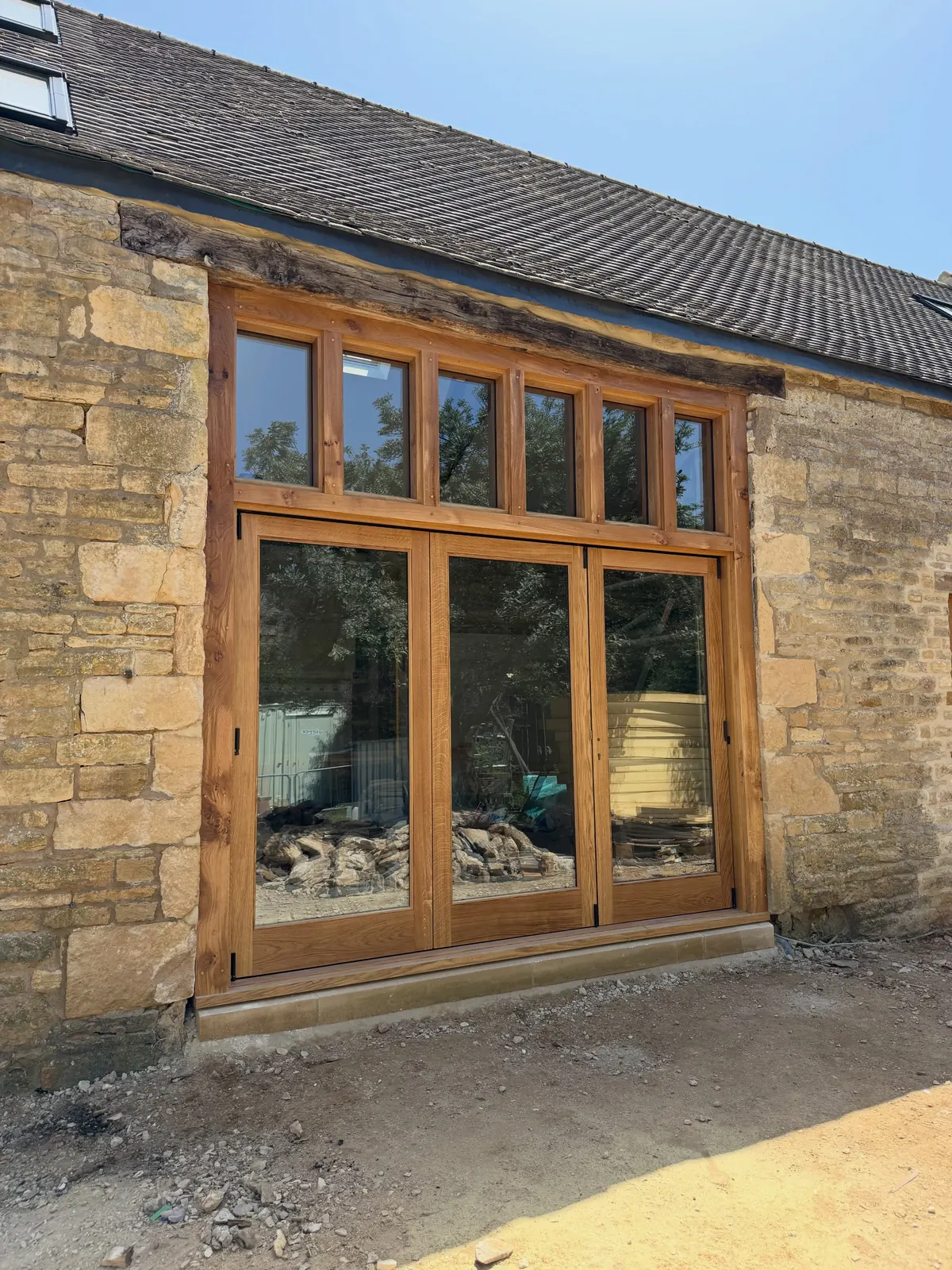 Oak-framed doors and a glazed screen set into a Cotswold stone barn