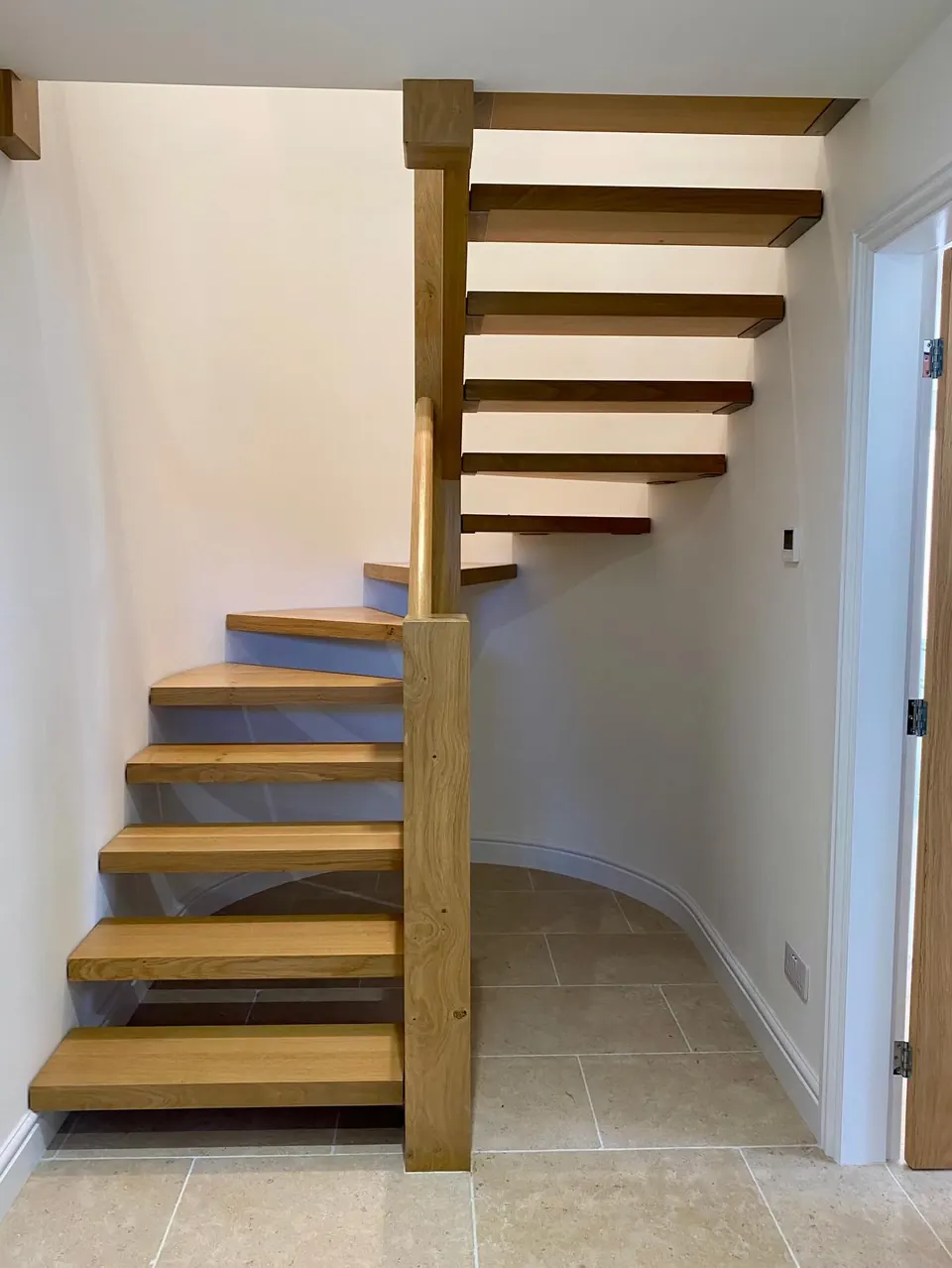 A semi-circular floating oak staircase with open treads