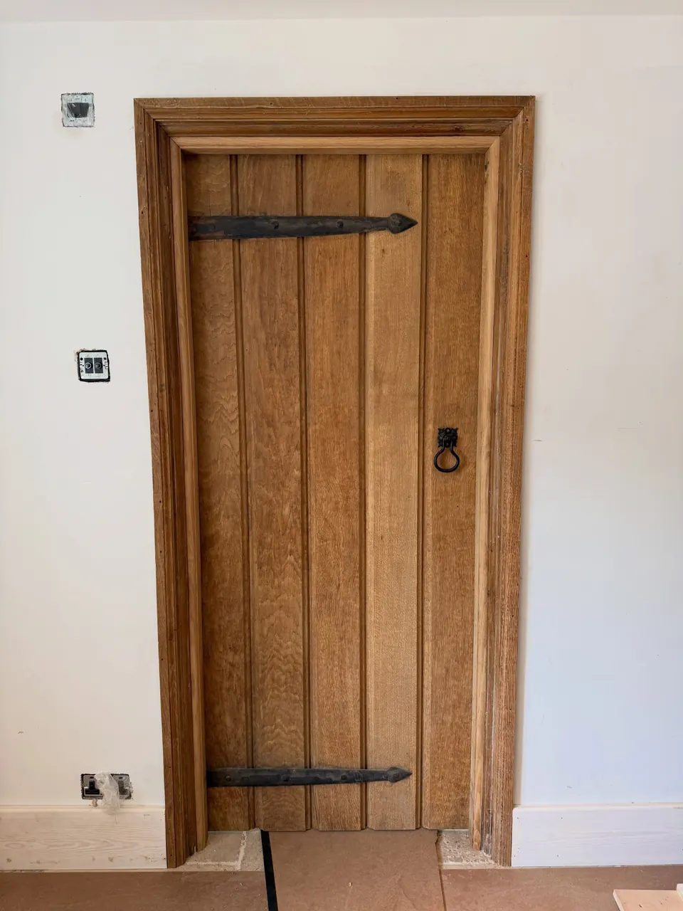 A solid oak ledged and braced door with iron strap hinges and a ring latch