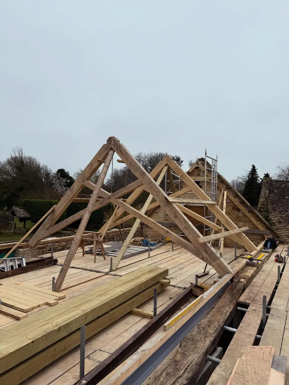 Two oak trusses standing on the roof deck against the sky