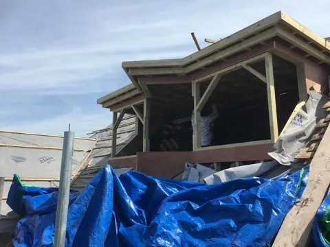 The dormer frame under construction behind scaffolding and tarpaulin