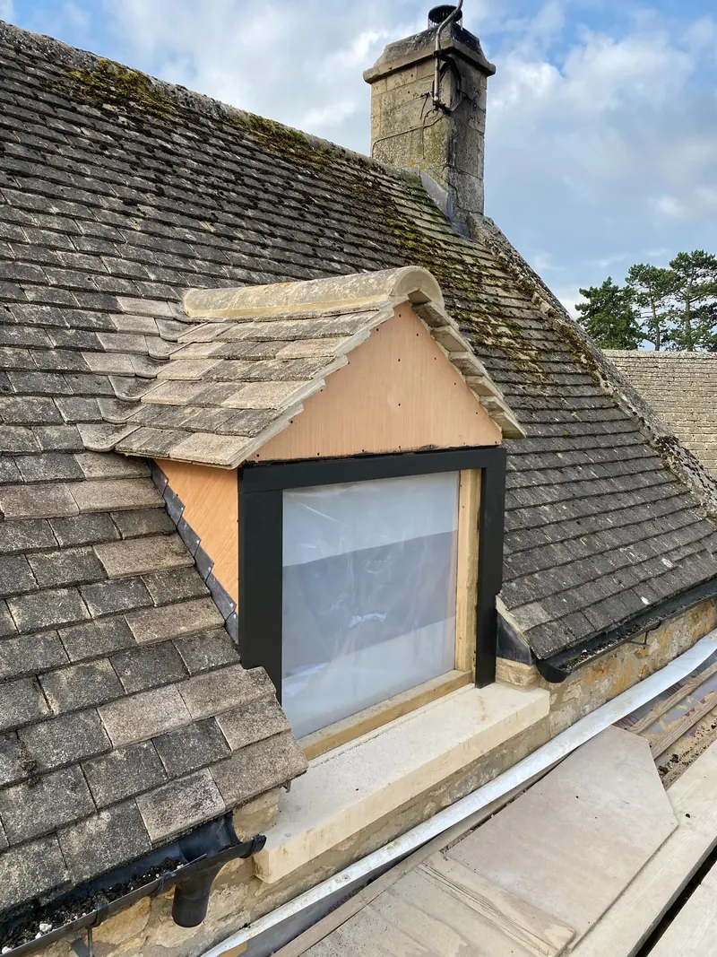A new dormer faced in natural stone tiles on a Cotswold stone roof