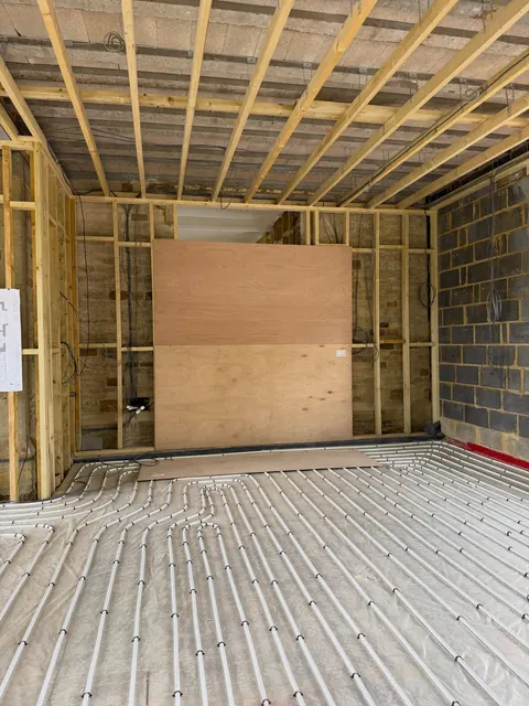 Inside the same job, with timber stud walls, ceiling joists and underfloor heating pipes