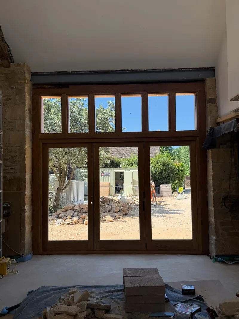 Oak bi-fold doors and a glazed top unit seen from inside a stone barn
