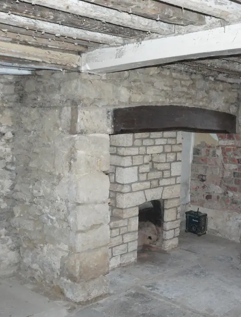 The inglenook before restoration, with the stonework and beam exposed