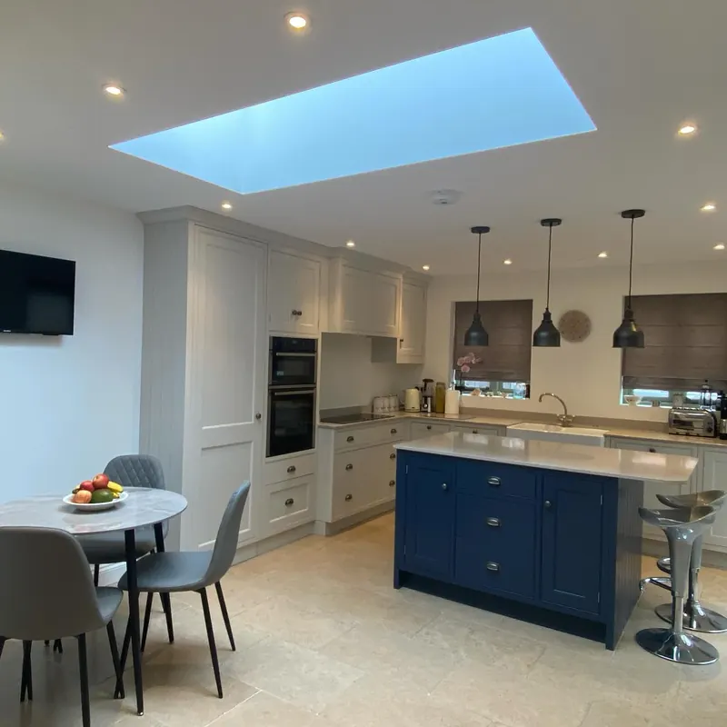 A shaker kitchen in Old English white with a blue island and a skylight above