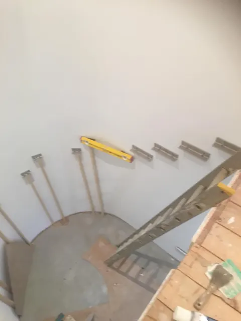 Steel brackets and a spirit level on the wall where the staircase was set out